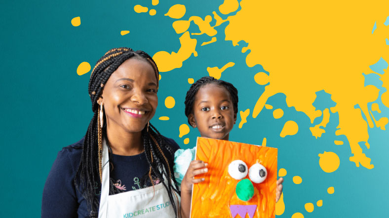mother and daughter pose with an orange canvas. a large yellow paint splatter is behind them on a blue gradient background